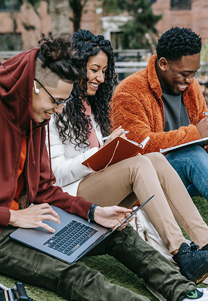 University students smile as they study outside.